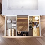 Badrum med snedtak inspiration, med badrumsmöbler i lila med eleganta ramfronter, vacker oval spegel med lampa, snygg och praktisk hylla, samt lilamålad vägg och grått fiskbensgolv som ger ett elegant och modernt uttryck.