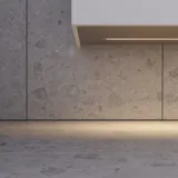 Modern och stilren badrumsinspiration med oval spegel med svart ram och ljusreglering, färgad toalett, tvättställsskåp, underskåp och skåp i rödbrun ek, Silestone handfat och matchande golv
