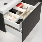 Stilfull badrumsinspiration med beige tvättställsskåp med innerskiva, överskåp, öppen hylla, ovalt spegel med belysning, matchande pendellampor, hylla under spegeln och vägghängd toalett. Väggar med ljusa, avlånga kakelplattor