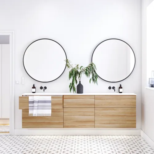 Nordiskt badrum i trä med vackra runda speglar med svarta kanter och gott om förvaring i badrumsmöblerna