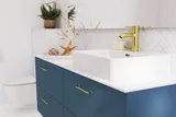 Badrumsinspiration med badrumsmöbler i modern blå färg, elegant fristående handfat och stor fyrkantig spegel med belysning, vita fiskbensplattor ger ett stilrent och klassiskt uttryck