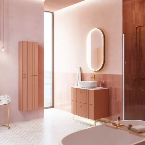 Stor vintage badrum med terrakottafärgat tvättställsskåp, bordstående handfat, ovalt spegel med mässingskant, ljusrosa och grå plattor ger ett romantiskt, feminint utseende