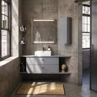 Badrumsinspiration med snedtak, grått tvättställsskåp och överskåp, specialtillverkade bänkskivor, modern fyrkantig fristående tvättställ, fyrkantig spegel med ljus, råa betongväggar och golv skapar en urban känsla