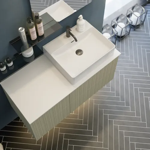 Badrum med snett tak inspiration, beige badrumsmöbler med räfflor, elegant bänkskiva och fyrkantigt bordsmonterat handfat, vacker fyrkantig spegel med stilfulla hyllor, blå väggar, stora fönster och svart fiskbensgolv ger ett ljust och urbant utseende.