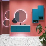 Stor badrumsinspiration med badrumsmöbler i blå specialfärg med räfflor, tunn elegant handfat samt vackra runda speglar, röda väggar och terrazzogolv skapar en stor kontrast till möblerna och ger ett stiligt och urbant utseende.