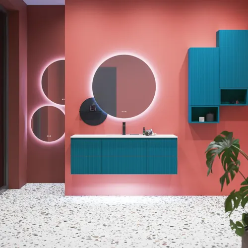 Stor badrumsinspiration med badrumsmöbler i blå specialfärg med räfflor, tunn elegant handfat samt vackra runda speglar, röda väggar och terrazzogolv skapar en stor kontrast till möblerna och ger ett stiligt och urbant utseende.