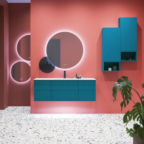 Stor badrumsinspiration med badrumsmöbler i blå specialfärg med räfflor, tunn elegant handfat samt vackra runda speglar, röda väggar och terrazzogolv skapar en stor kontrast till möblerna och ger ett stiligt och urbant utseende.