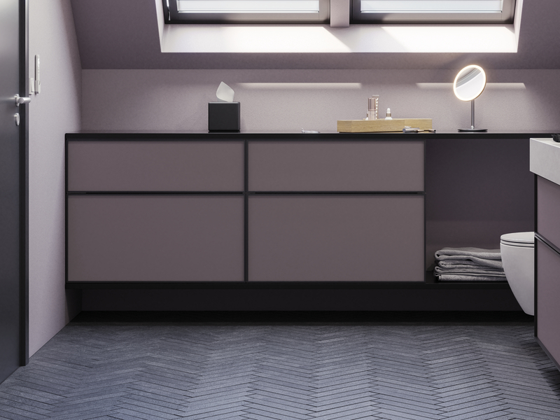 Badrum med snedtak inspiration, med badrumsmöbler i lila med eleganta ramfronter, vacker oval spegel med lampa, snygg och praktisk hylla, samt lilamålad vägg och grått fiskbensgolv som ger ett elegant och modernt uttryck.