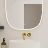 Elegant och modern badrumsinspiration med snedtak, väggmonterade blå tvättställsskåp och underskåp, rund handfat med mässingsarmatur, belyst spegel och naturligt ljusinsläpp