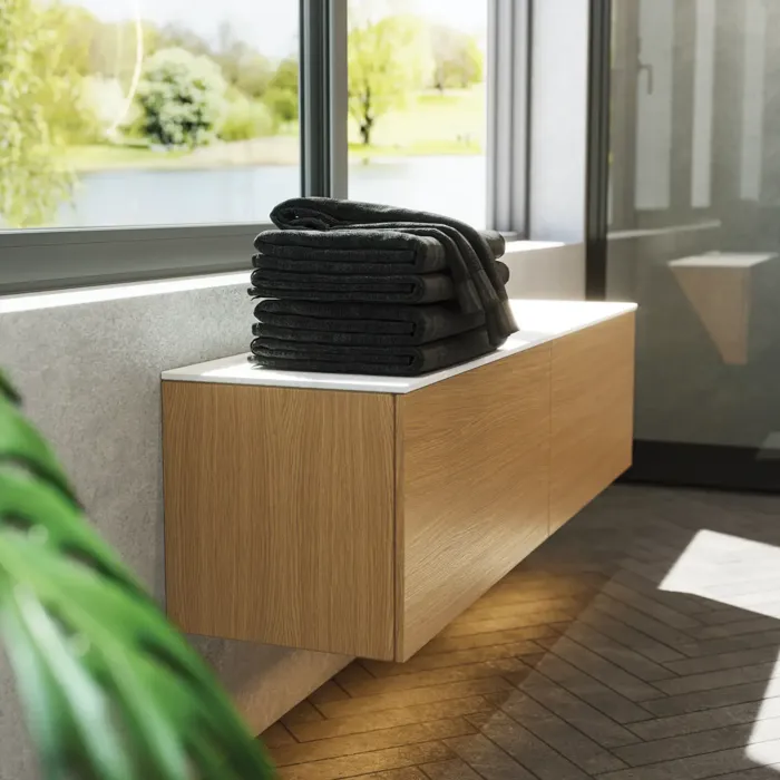 Minimalistisk och stilren badrumsinspiration med tvättställsskåp, underskåp och högskåp i gyllene ek, stor rund spegel med ljusreglering, färgad toalett och fristående handfat