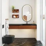 Modern och stilren badrumsinspiration med oval spegel med svart ram och ljusreglering, färgad toalett, tvättställsskåp, underskåp och skåp i rödbrun ek, Silestone handfat och matchande golv