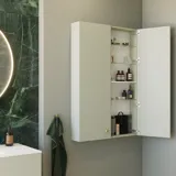 Stilrent och lyxigt badrum med mjuka gröna nyanser, en stor elegant rund spegel och en modern, sofistikerad grön toalett