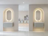 Stilfull och modern badrumsinspiration med ovala speglar med ljusreglering, stenhandfat och tvättställsskåp med fina och eleganta räfflor i en minimalistisk design, badrummet har en ljus och luftig atmosfär med elegant belysning och raffinerade detaljer