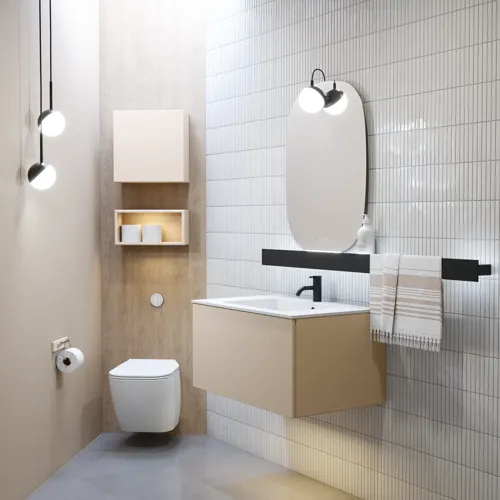 Stilfull badrumsinspiration med beige tvättställsskåp med innerskiva, överskåp, öppen hylla, ovalt spegel med belysning, matchande pendellampor, hylla under spegeln och vägghängd toalett. Väggar med ljusa, avlånga kakelplattor