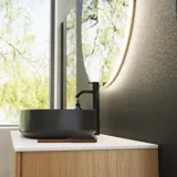 Minimalistisk och stilren badrumsinspiration med tvättställsskåp, underskåp och högskåp i gyllene ek, stor rund spegel med ljusreglering, färgad toalett och fristående handfat