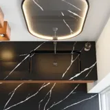 Modern och stilren badrumsinspiration med oval spegel med svart ram och ljusreglering, färgad toalett, tvättställsskåp, underskåp och skåp i rödbrun ek, Silestone handfat och matchande golv
