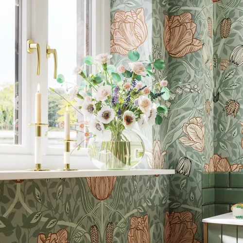 Badrumsinspiration med badrumsmöbler i grön specialfärg med sidor i naturlig ek, eleganta räfflor, stilfull bänkskiva med romantiskt ovalt bordsmonterat handfat, vacker oval spegel, ger tillsammans med blommigt tapet ett graciöst, vintage retro utseende.