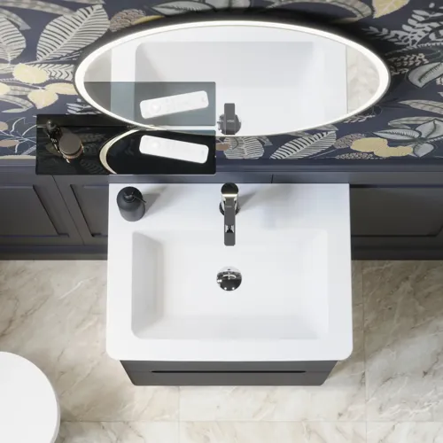 Badrumsinspiration med mörkblå väggpaneler, romantisk blommig tapet, mörkblått tvättställsskåp med mjuka former och en vacker rund spegel med ljus som skapar en vintagekänsla