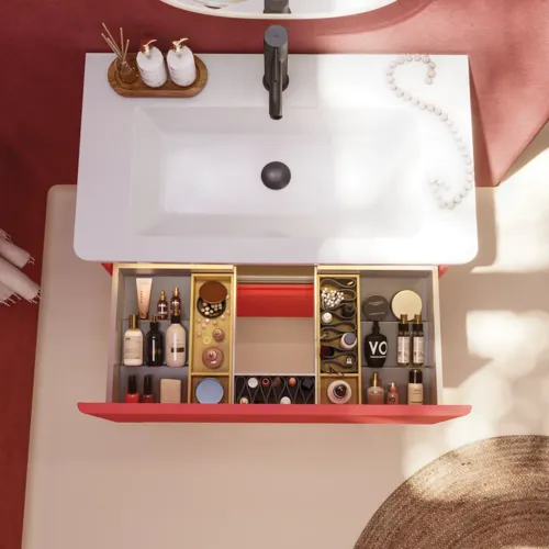 Badrumsinspiration med röda väggar, mjukt formade röda tvättställsskåp och högskåp, elegant vit handfat och en vacker oval spegel med ljus som tillsammans med den naturliga omgivningen skapar en vintagekänsla