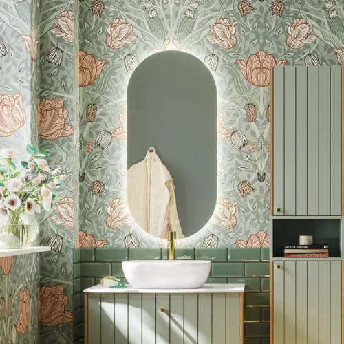 Badrumsinspiration med badrumsmöbler i grön specialfärg med sidor i naturlig ek, eleganta räfflor, stilfull bänkskiva med romantiskt ovalt bordsmonterat handfat, vacker oval spegel, ger tillsammans med blommigt tapet ett graciöst, vintage retro utseende.