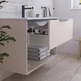 Badrumsinspiration med rosa underskåp med eleganta spår och vackert handfat, vitt kakel på väggarna och stora beige plattor på golvet skapar en romantisk och feminin look.