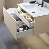 Stilfull badrumsinspiration med beige tvättställsskåp med innerskiva, överskåp, öppen hylla, ovalt spegel med belysning, matchande pendellampor, hylla under spegeln och vägghängd toalett. Väggar med ljusa, avlånga kakelplattor