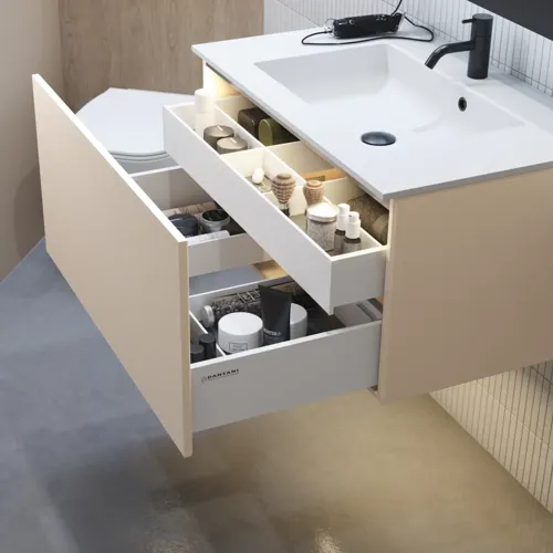 Stilfull badrumsinspiration med beige tvättställsskåp med innerskiva, överskåp, öppen hylla, ovalt spegel med belysning, matchande pendellampor, hylla under spegeln och vägghängd toalett. Väggar med ljusa, avlånga kakelplattor