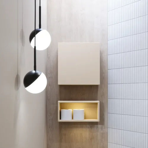 Stilfull badrumsinspiration med beige tvättställsskåp med innerskiva, överskåp, öppen hylla, ovalt spegel med belysning, matchande pendellampor, hylla under spegeln och vägghängd toalett. Väggar med ljusa, avlånga kakelplattor
