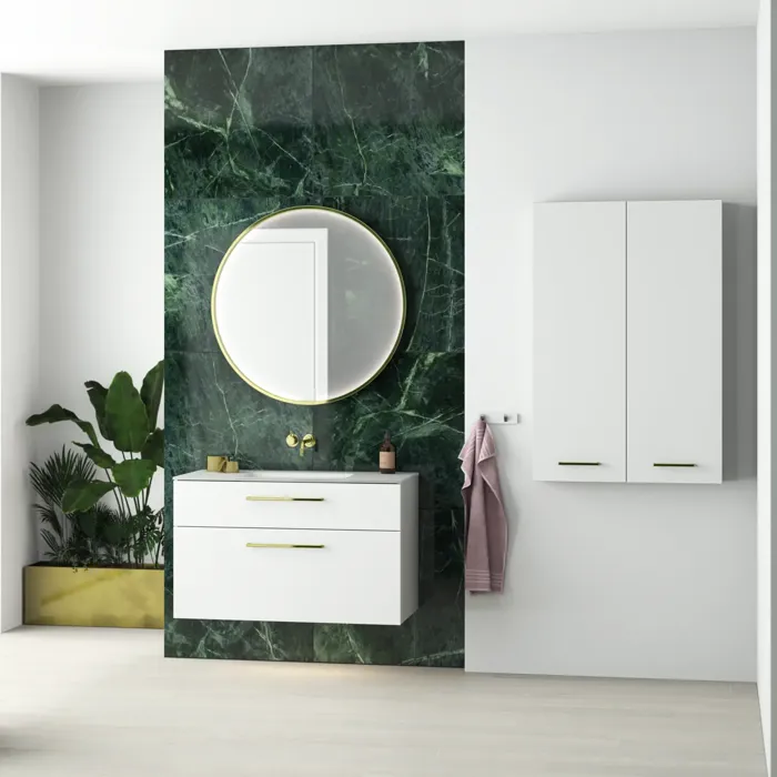 Stilrent och lyxigt badrum med mörkgrön marmorerad vägg, stor elegant rund spegel och moderna vita badrumsmöbler.