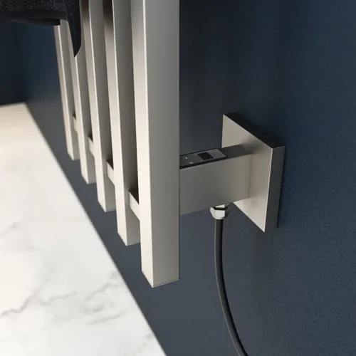 Elektrisk handdukstork på mörkblå vägg i stilrent badrum.