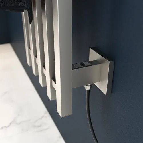 Elektrisk handdukstork på mörkblå vägg i stilrent badrum.