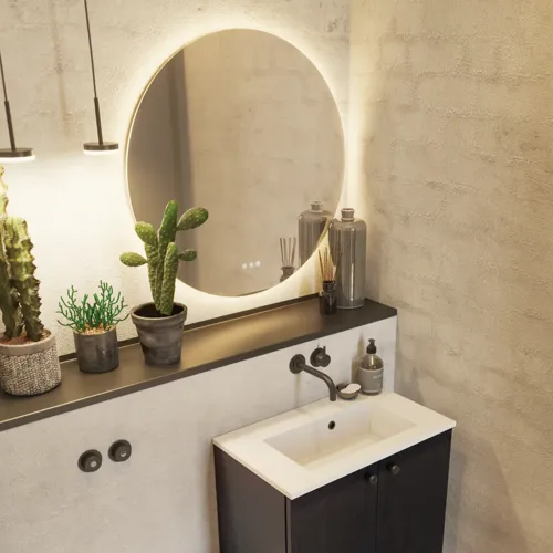 Badrumsinspiration med tvättställsskåp i svart ek samt elegant runt spegel och handfat, snygga tillbehör samt kaktusväxter och väggar i råa material ger ett rått, industriellt och urbant utseende.