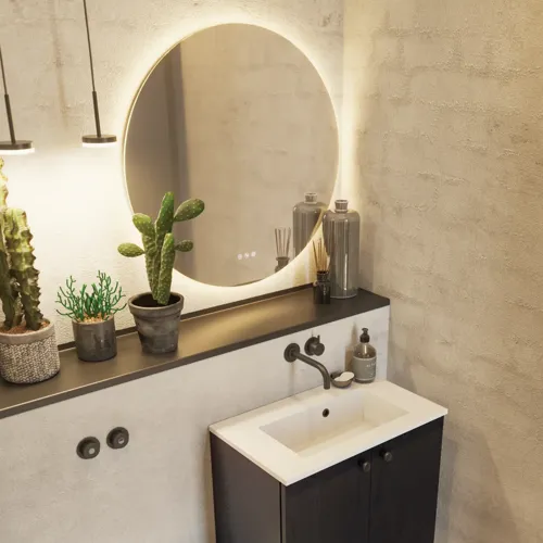 Badrumsinspiration med tvättställsskåp i svart ek samt elegant runt spegel och handfat, snygga tillbehör samt kaktusväxter och väggar i råa material ger ett rått, industriellt och urbant utseende.