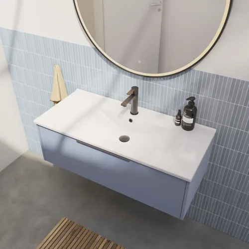 Badrumsinspiration med avlånga ljusblå kakelplattor och betonggolv, elegant tvättställsskåp i ljusblått med vackra smala ränder, stilren och tunn handfat samt en minimalistisk rund spegel med svart kant och belysning.