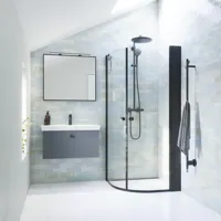 Badrumsinspiration med grått underdel med fyrkantig spegel med svart kant och lampa, rundade duschdörrar i klarglas och profiler i svart matt, med elektrisk handdukstork och badrumshylla.