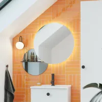 Badrum med snedtak inspiration med liten vit kommod och högskåp med runda svarta handtag, samt vacker rund spegel, orange kakel ger ett fräscht och modernt utseende.