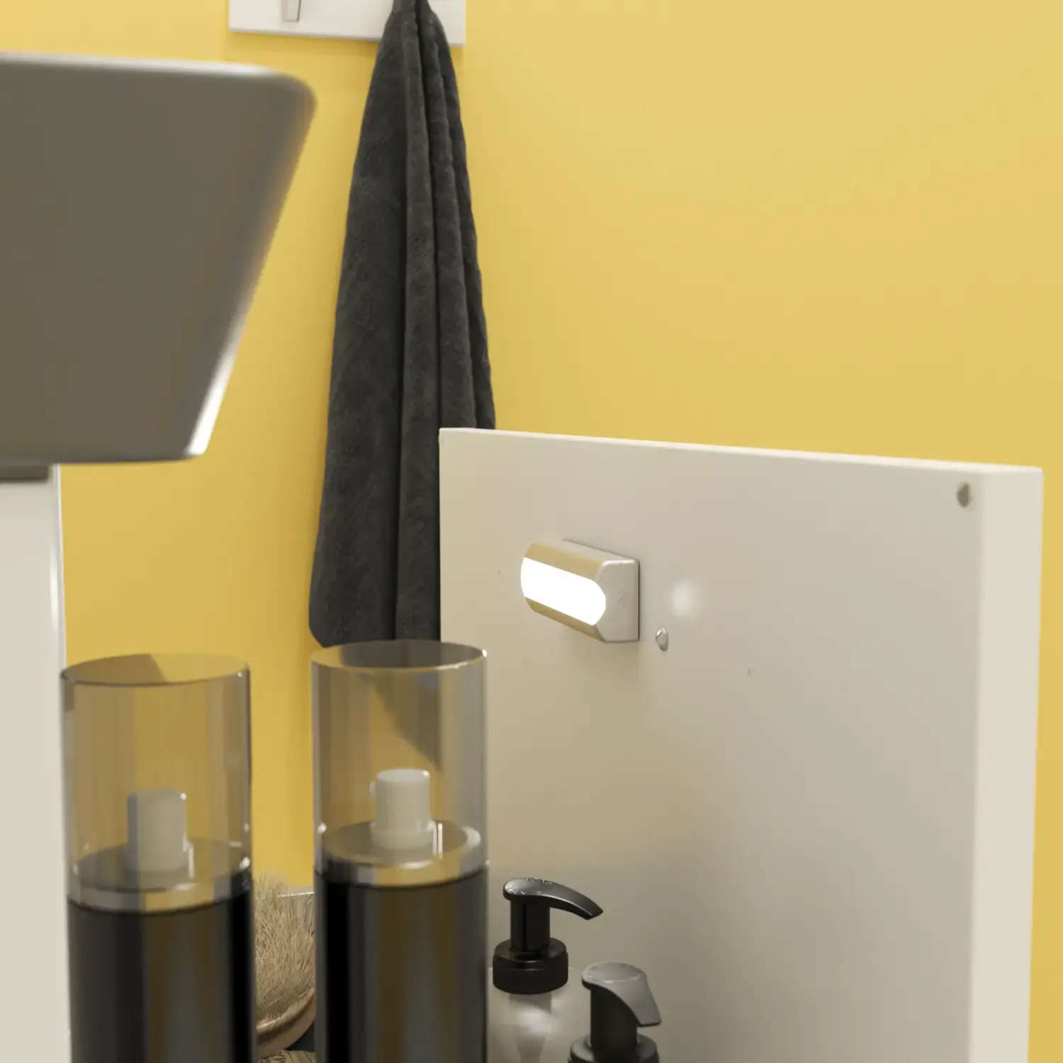 Liten badrumsinspiration med vitt tvättställsskåp med svart handtag och svart elegant handfat, vacker rund spegel med svart kant, förskjutna överskåp samt terrazzo vägg och golv och gula väggar ger ett modigt och modernt utseende.