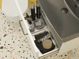 Liten badrumsinspiration med vitt tvättställsskåp med svart handtag och svart elegant handfat, vacker rund spegel med svart kant, förskjutna överskåp samt terrazzo vägg och golv och gula väggar ger ett modigt och modernt utseende.