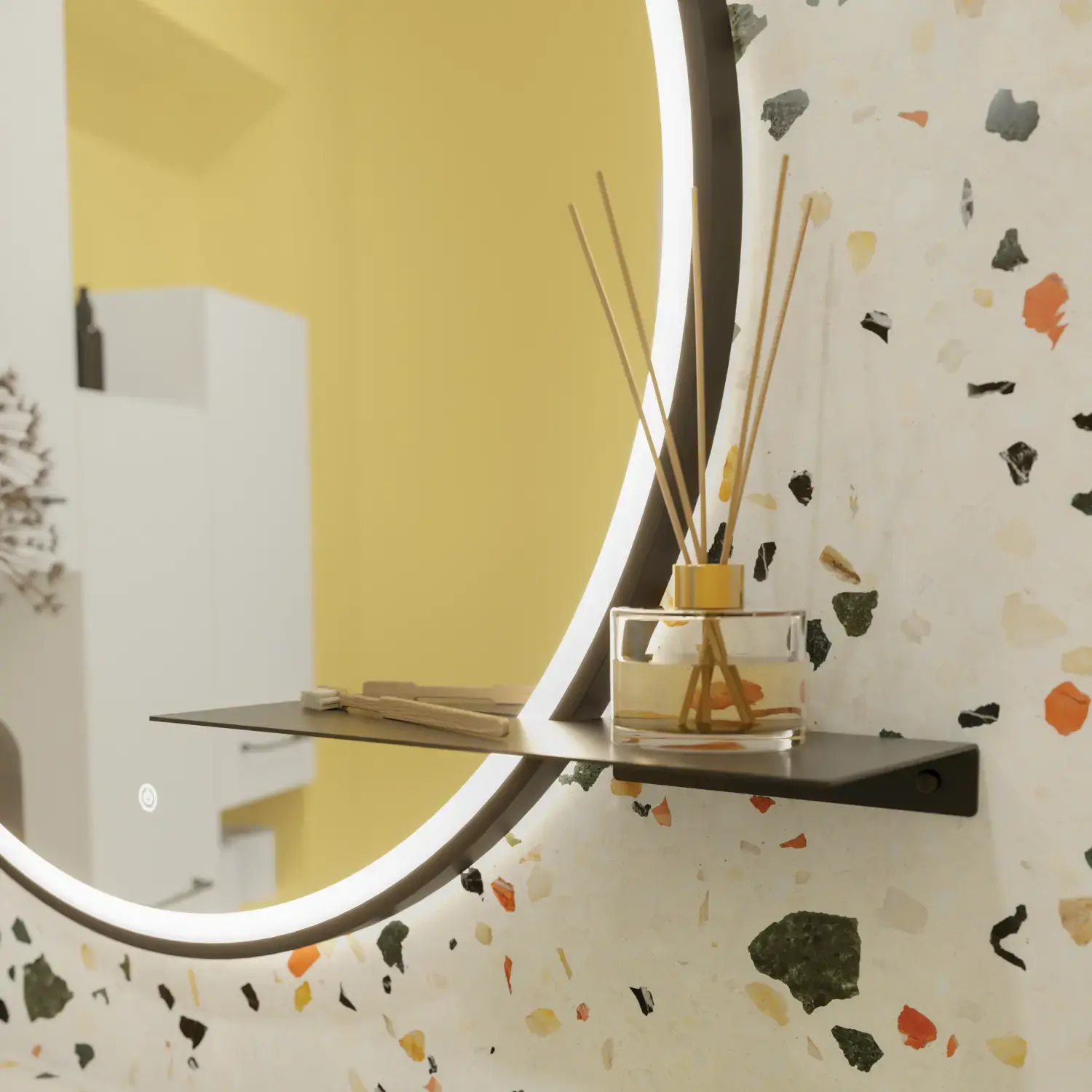 Liten badrumsinspiration med vitt tvättställsskåp med svart handtag och svart elegant handfat, vacker rund spegel med svart kant, förskjutna överskåp samt terrazzo vägg och golv och gula väggar ger ett modigt och modernt utseende.