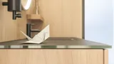 Stilrent badrum i skandinavisk och japandi inredningsstil med ljusa träväggar, rund spegel och minimalistiska badrumsmöbler.