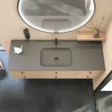 Stilrent badrum i skandinavisk och japandi inredningsstil med ljusa träväggar, rund spegel och minimalistiska badrumsmöbler.