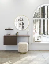 Nordisk stil badrumsinspiration med tvättställsskåp och underskåp i rökt ek, sminkplats, sidoplacerat handfat, rund spegel med mässingsram och synliga charmiga träbjälkar.