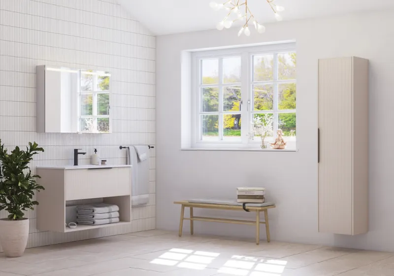 Stor badrumsinspiration med små avlånga plattor, feminin ljuskrona, elegant underskåp och högskåp i ljusbeige med vackra smala ränder, svarta moderna avlånga handtag och snyggt spegelskåp med belysning för att skapa en romantisk atmosfär.
