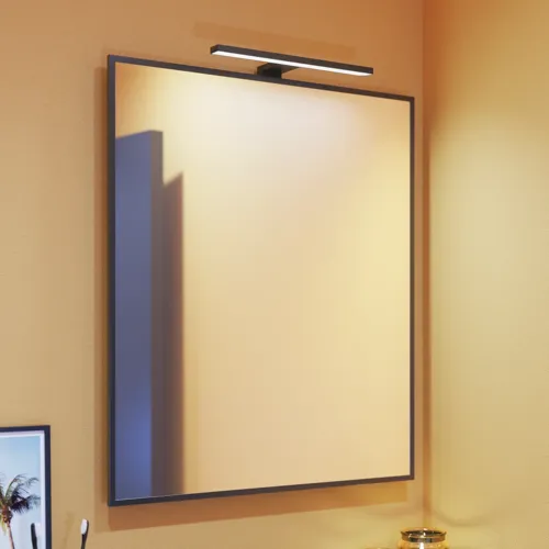 Liten badrumsinspiration med sneda och varma gula väggar, och en minimalistisk fyrkantig spegel med stilren svart kant, samt en elegant lampa till spegeln, som ger ett stänk av elegans till ditt badrum.