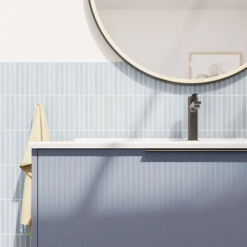 Badrumsinspiration med avlånga ljusblå kakelplattor och betonggolv, elegant tvättställsskåp i ljusblått med vackra smala ränder, stilren och tunn handfat samt en minimalistisk rund spegel med svart kant och belysning.
