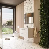 Stor badrumsinspiration med badrumsmöbler i mattvitt med elegant handfat och fyrkantig spegel med svart kant och lampa, terrazzo vägg och golv och växter på väggen för en modern och sofistikerad look.