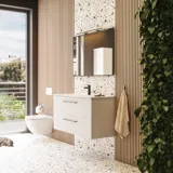 Stor badrumsinspiration med badrumsmöbler i mattvitt med elegant handfat och fyrkantig spegel med svart kant och lampa, terrazzo vägg och golv och växter på väggen för en modern och sofistikerad look.
