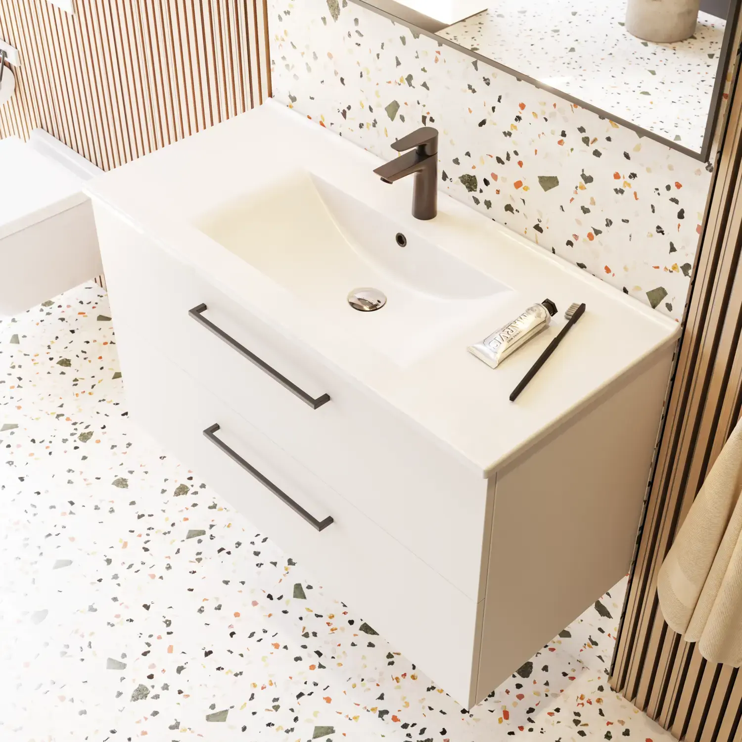 Stor badrumsinspiration med badrumsmöbler i mattvitt med elegant handfat och fyrkantig spegel med svart kant och lampa, terrazzo vägg och golv och växter på väggen för en modern och sofistikerad look.