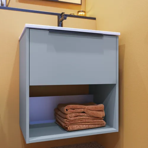 Liten badrumsinspiration med sneda och varma gula väggar, elegant tvättställsskåp i ljusblått med öppen hylla som skapar en unik atmosfär, tunn och stilren handfat som tillför både praktisk funktion och elegans till ditt badrum.