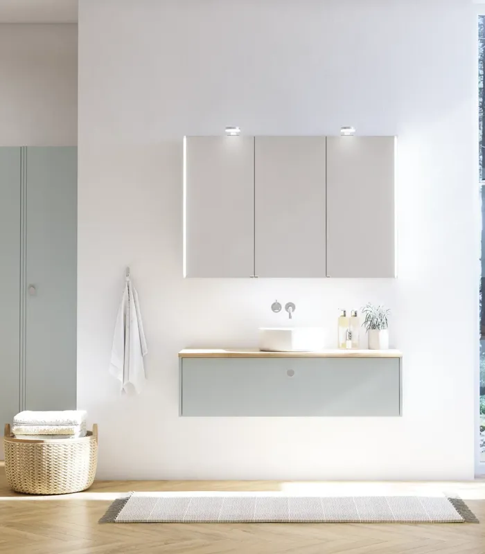 Stor badrumsinspiration i nordisk stil med badrumsmöbler i ljusblå färg och träbänkskiva med elegant fristående handfat, fiskbensgolv i trä som skapar en ljus och klassisk stil